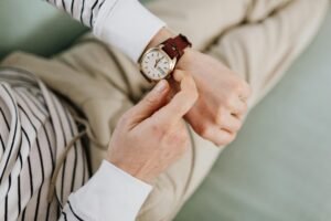 A person adjusts an analog wristwatch with a leather strap, showcasing style and precision.